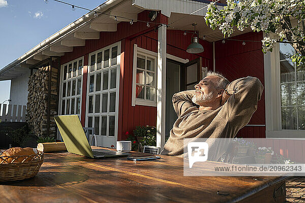 Freelancer with laptop on table resting outside house