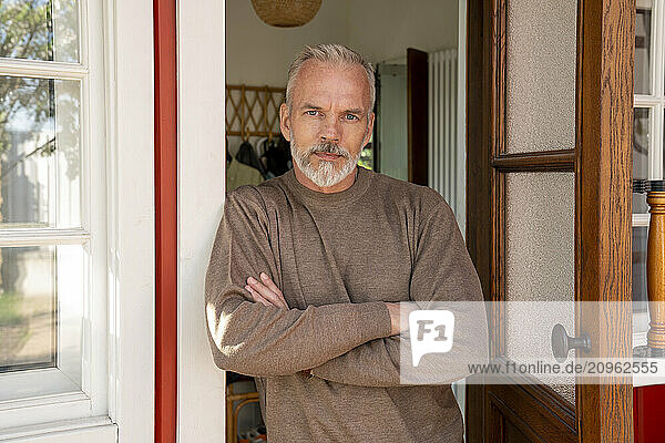 Man with arms crossed leaning at doorway