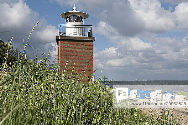 Germany  Schleswig-Holstein  Wyk  Beachside lighthouse with hooded beach chairs in background