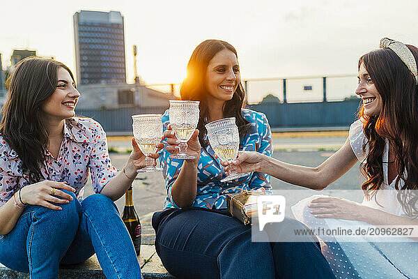 Happy friends toasting wineglasses together at sunset