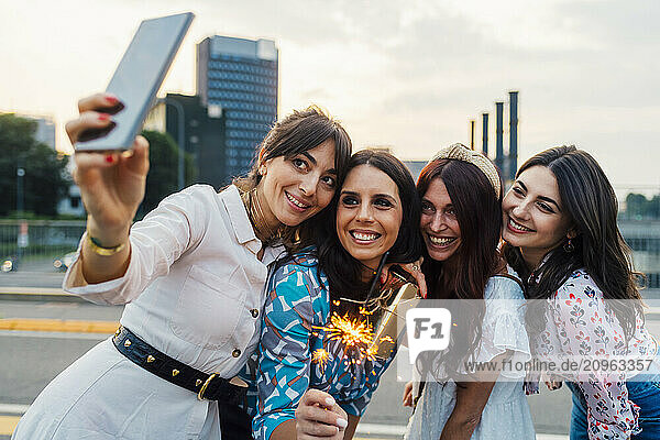 Happy woman taking selfie with friends at sunset