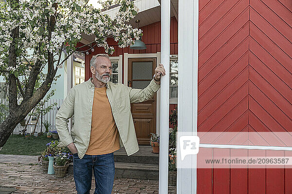 Thoughtful man standing near house in back yard