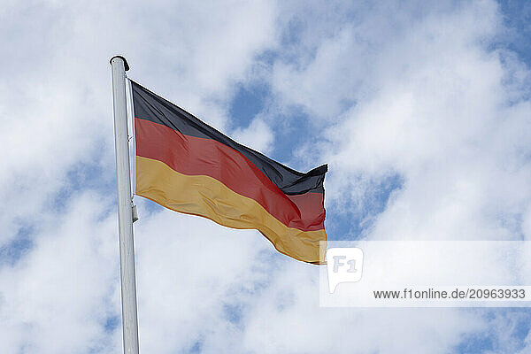Germany  Schleswig-Holstein  German flag on flagpole standing against clouds