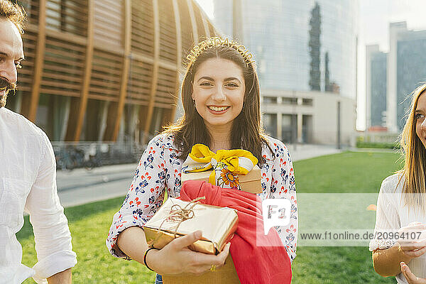 Happy woman holding gifts with friends