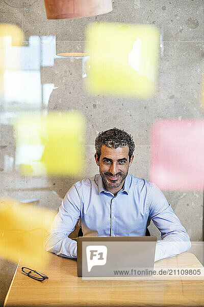 Smiling businessman working on laptop sitting at co working space