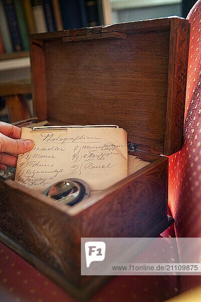 A woman takes a handwritten old letter out of an opened old wooden box representing memories and family history.