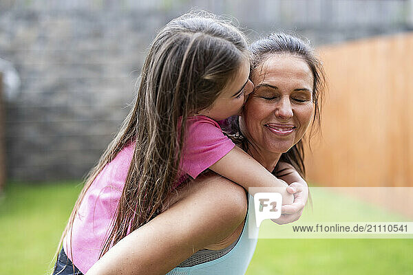Daughter kissing mother in back yard