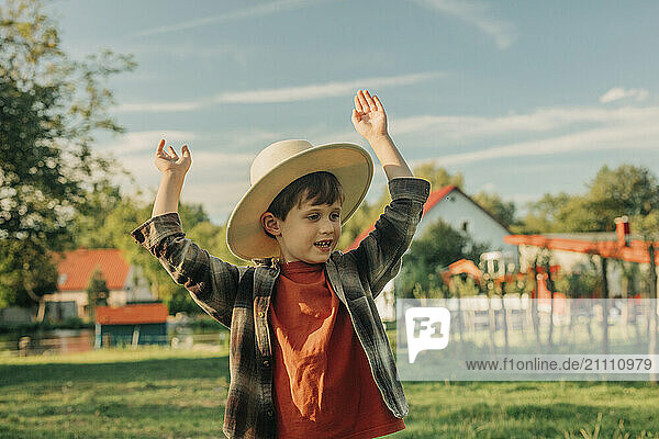 Playful boy with arms raised in farm