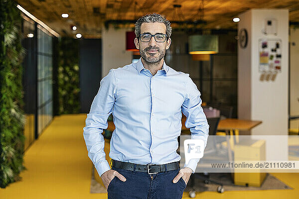 Businessman standing with hands in pocket at co working space