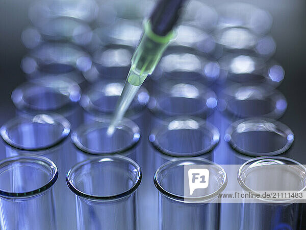 Pipette extracting samples from test tubes in laboratory