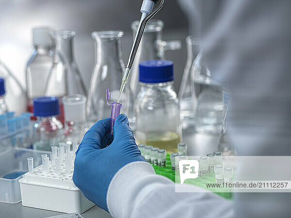 Hand of scientist analyzing DNA samples using vial and pipette in laboratory