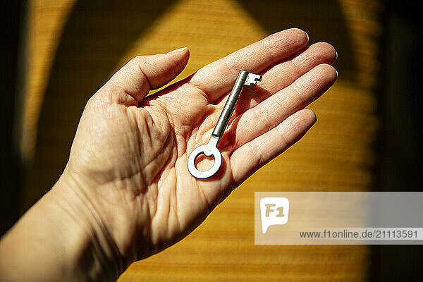 A woman holds an old key in her hand symbolizing genealogy and inheritance.