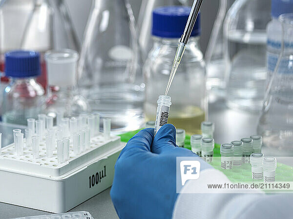 Hand of scientist preparing DNA samples using test tube and pipette in laboratory
