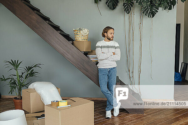 Young man standing by staircase with arms crossed