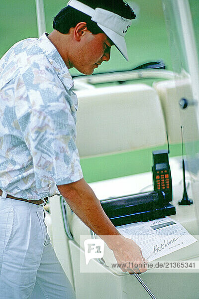 Business executive using document transmission equipment on golf buggy.