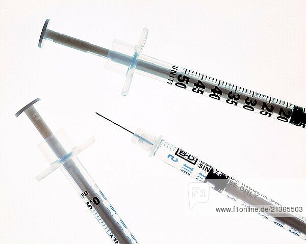Still life of three hypodermic syringes.