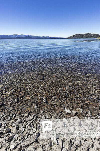 Rocky beach and calm lake on sunny day