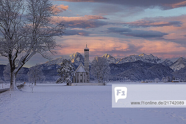 Blick auf Sankt Coloman in Schwangau im Winter mit Schnee  im Hintergrund die Allgäuer Alpen