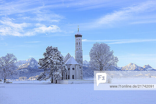 Blick auf Sankt Coloman in Schwangau im Winter mit Schnee  im Hintergrund die Allgäuer Alpen