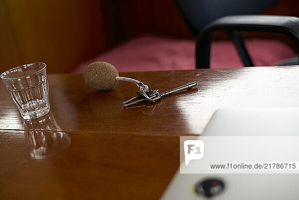A wooden table with a glass of water  hotel keys  and a laptop partially visible  Teheran  Iran