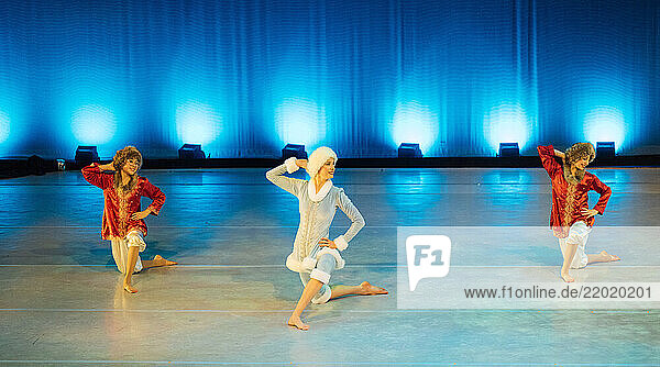 Three dancers in colorful costumes perform on a well-lit stage with a blue backdrop. The Nutcracker  Bainbridge Island  USA