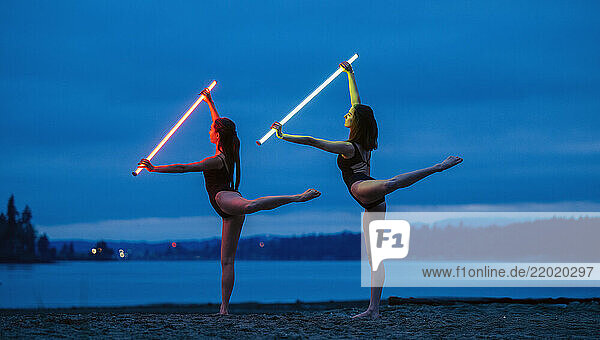 Two dancers on a beach illuminate the night sky with vibrant  glowing light sabers  USA