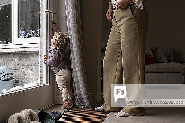 Toddler trying to escape while standing beside an adult inside a cozy living room. Netherlands