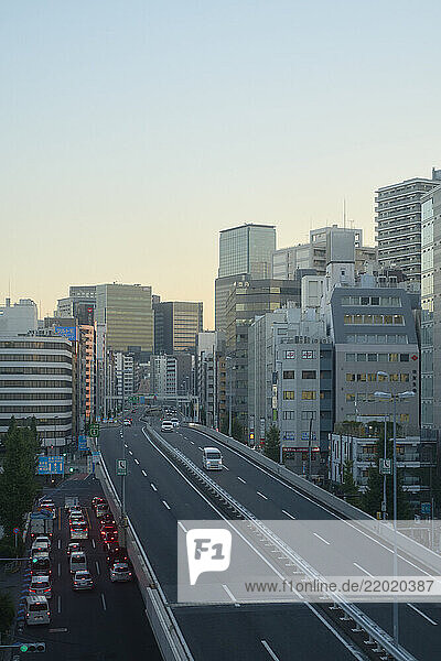 Urban highway leads into a cityscape of tall buildings at dawn with light traffic. Tokyo  Japan