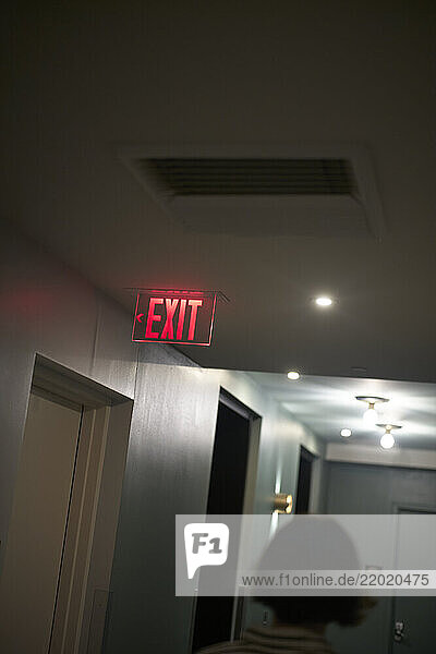 Dimly lit hallway with a glowing red exit sign and partially visible person  Miami  FLorida  USA