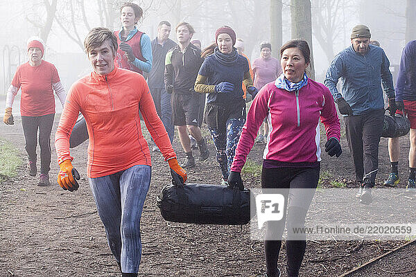 A group of diverse adults jogs on a forest trail in misty weather  dressed in colorful activewear. They are visibly energetic and focused. Sale Water Park  Manchester  UK
