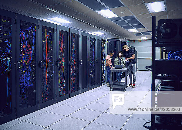 Group of technicians using laptop in server room