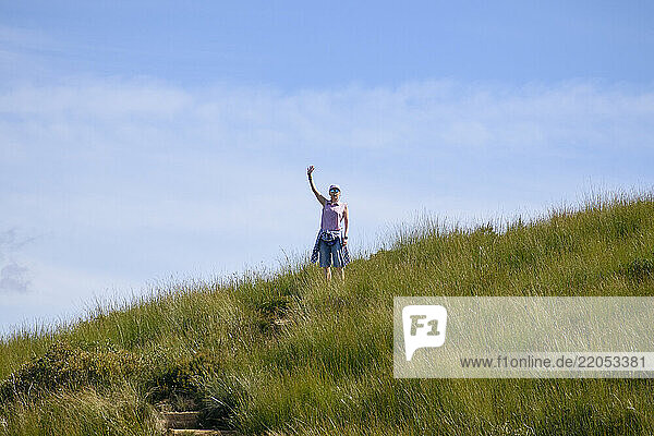 Woman in sunglasses standing on grassy field and waving