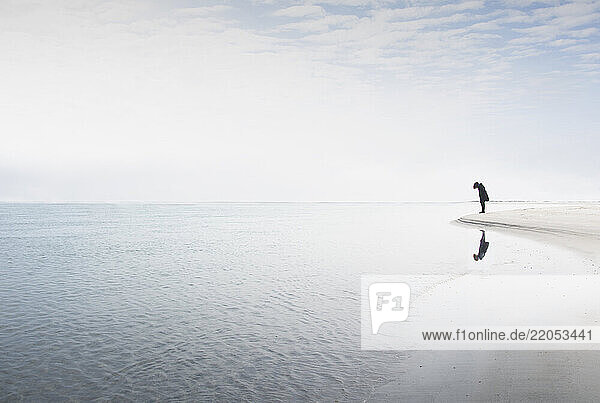 Silhouette of woman staring at edge of water