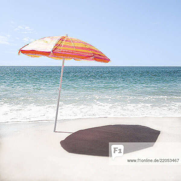 Lone orange beach umbrella on empty Surfside Beach