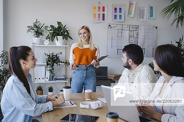 Smiling blond businesswoman explaining ideas to colleagues in meeting at office