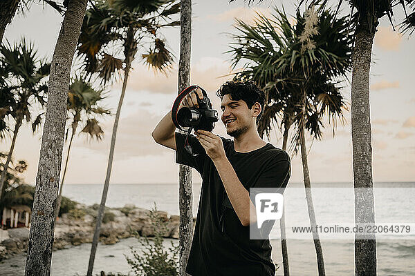 Mexico  Quintana Roo  Tulum  young man taking pictures on the beach