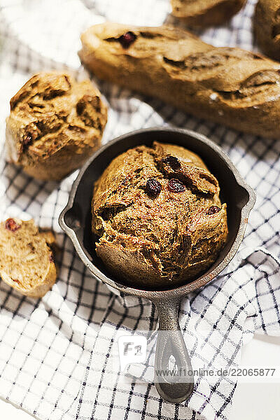 Homemade rye sourdough bread with raisins in a cast iron pan on a kitchen towel  representing traditional Ukrainian baking.