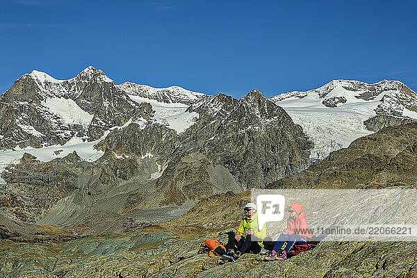 Hikers sitting on Monte Disgrazia under clear blue sky