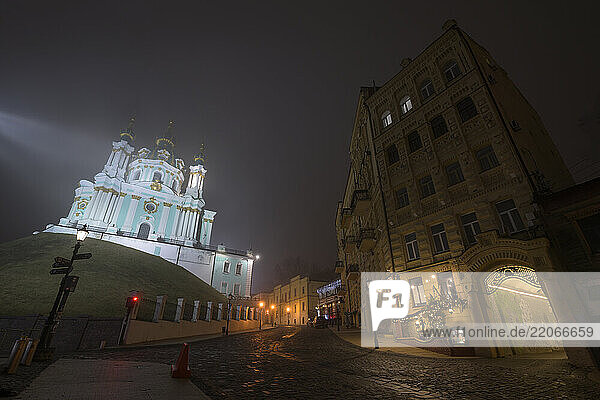 Saint-Andreas church in Kyiv  Ukraine at night with fog and cobblestone street