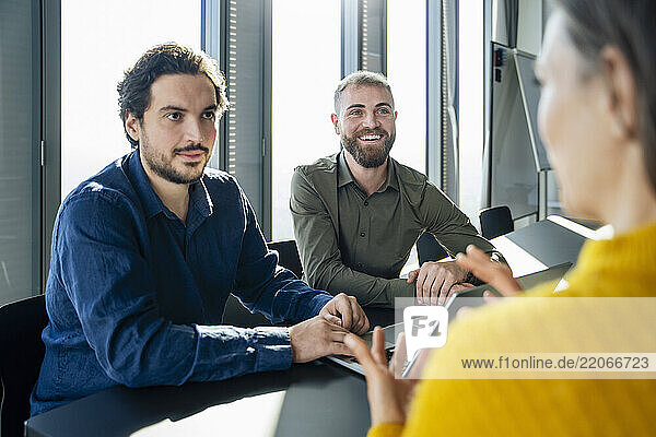 Happy businessmen discussing with colleague in office