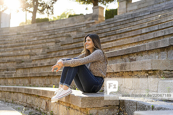 Happy young woman sitting on stairs outdoors