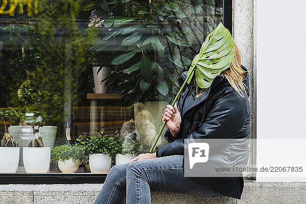 Blonde woman smiling with a leaf on a city street