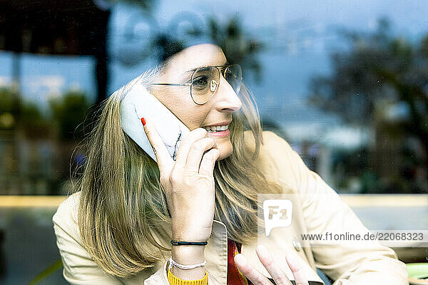 Woman behind windowpane on cell phone in a cafe