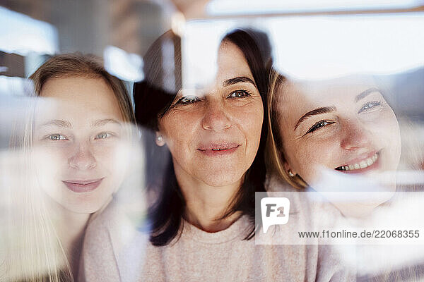 Visiting daughters embracing their mother  standing at the window