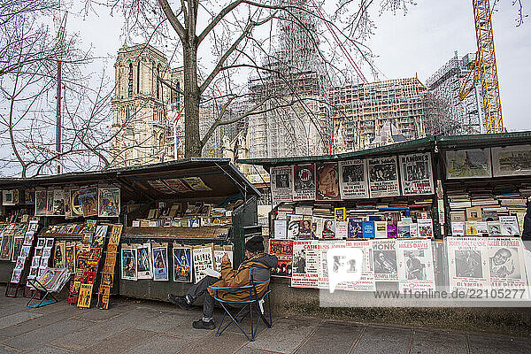 France  Paris  75  1er arrondissement  Quai de Montebello  bouqiniste assis devant ses boîtes  déc 2024.
