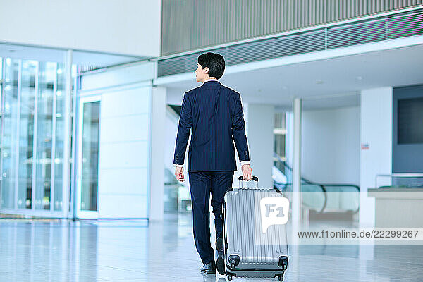 Japanese Man In A Suit Walking With A Suitcase