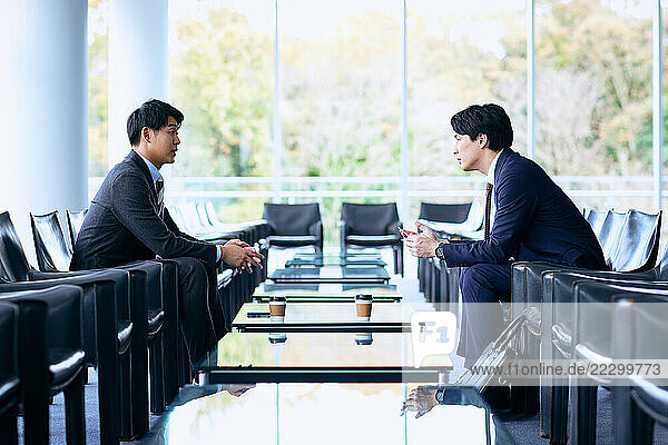 Two Businessmen Sitting At A Table In An Office