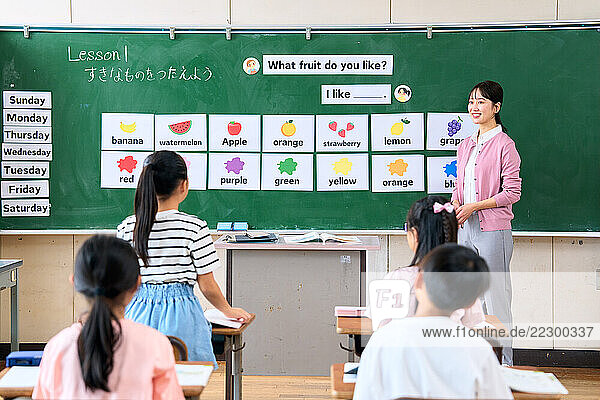 Japanese Teacher With Her Students In Front Of A Blackboard