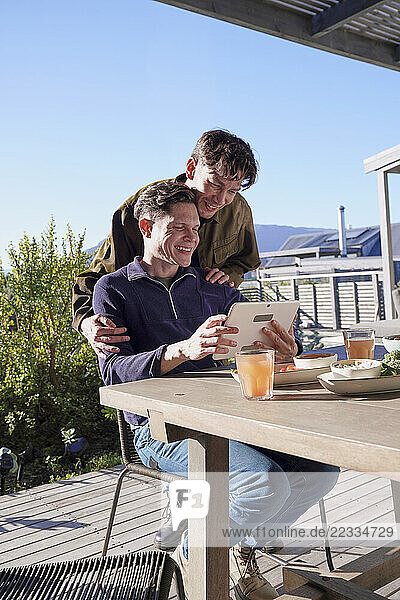 Gay couple looking at digital tablet on patio