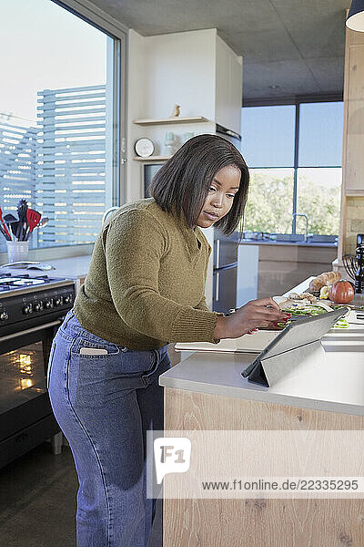 Woman using digital tablet in kitchen